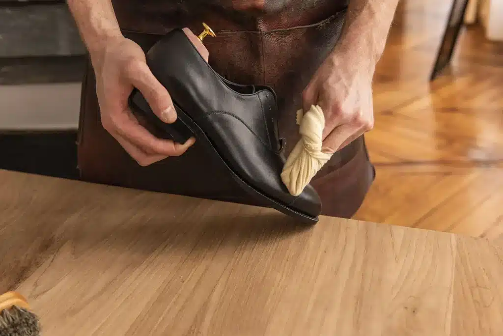 Application de crème de cirage sur une chaussure en cuir lisse avec une chamoisine